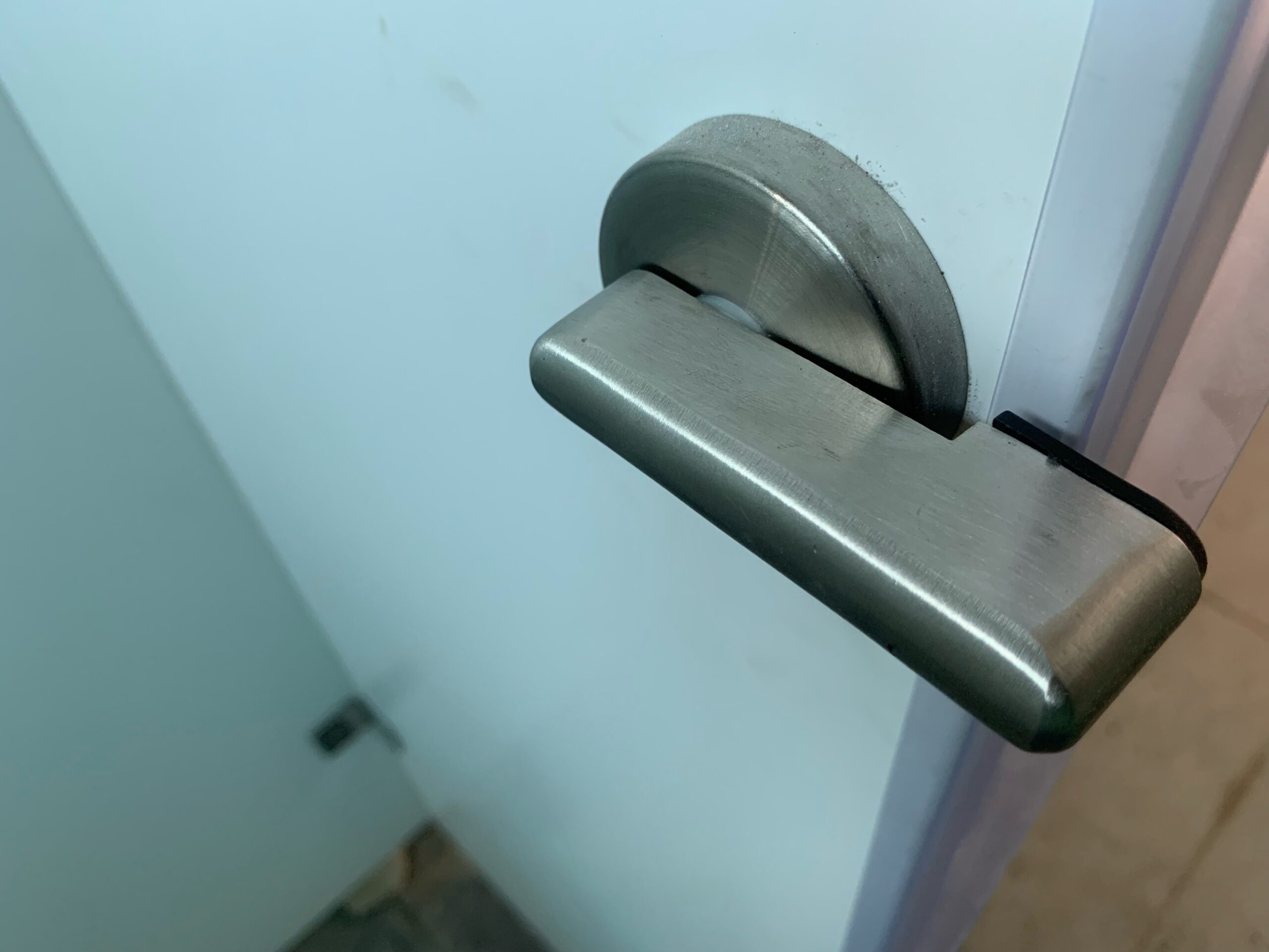 Las soluciones de bandas de privacidad para mamparas de aseos amplían la privacidad de un cubículo de aseo, como se ilustra en esta imagen de una puerta de separación, un borde y un tirador.