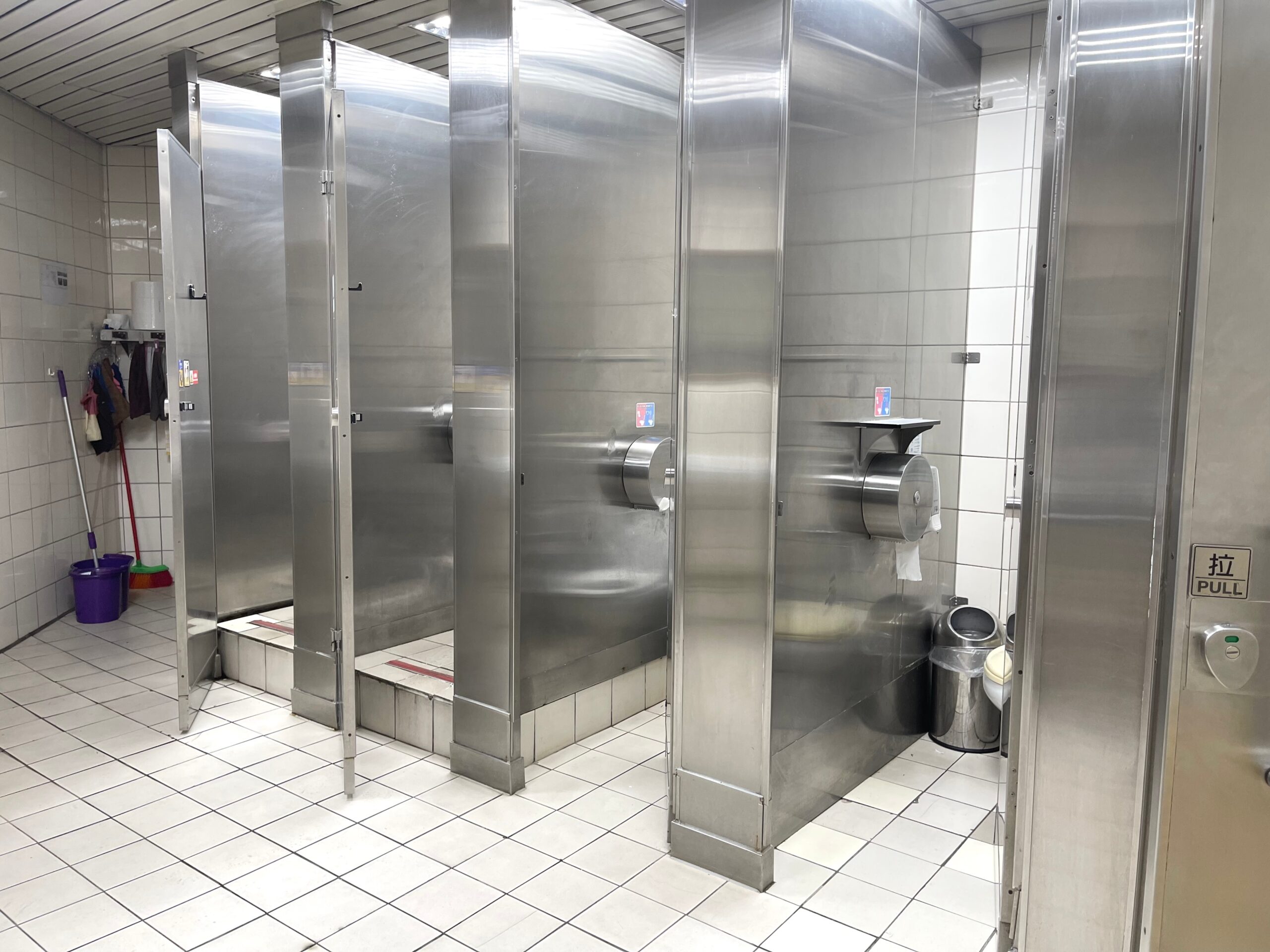Stainless steel toilet stall dividers in a medium-size public restroom that gets high usage.