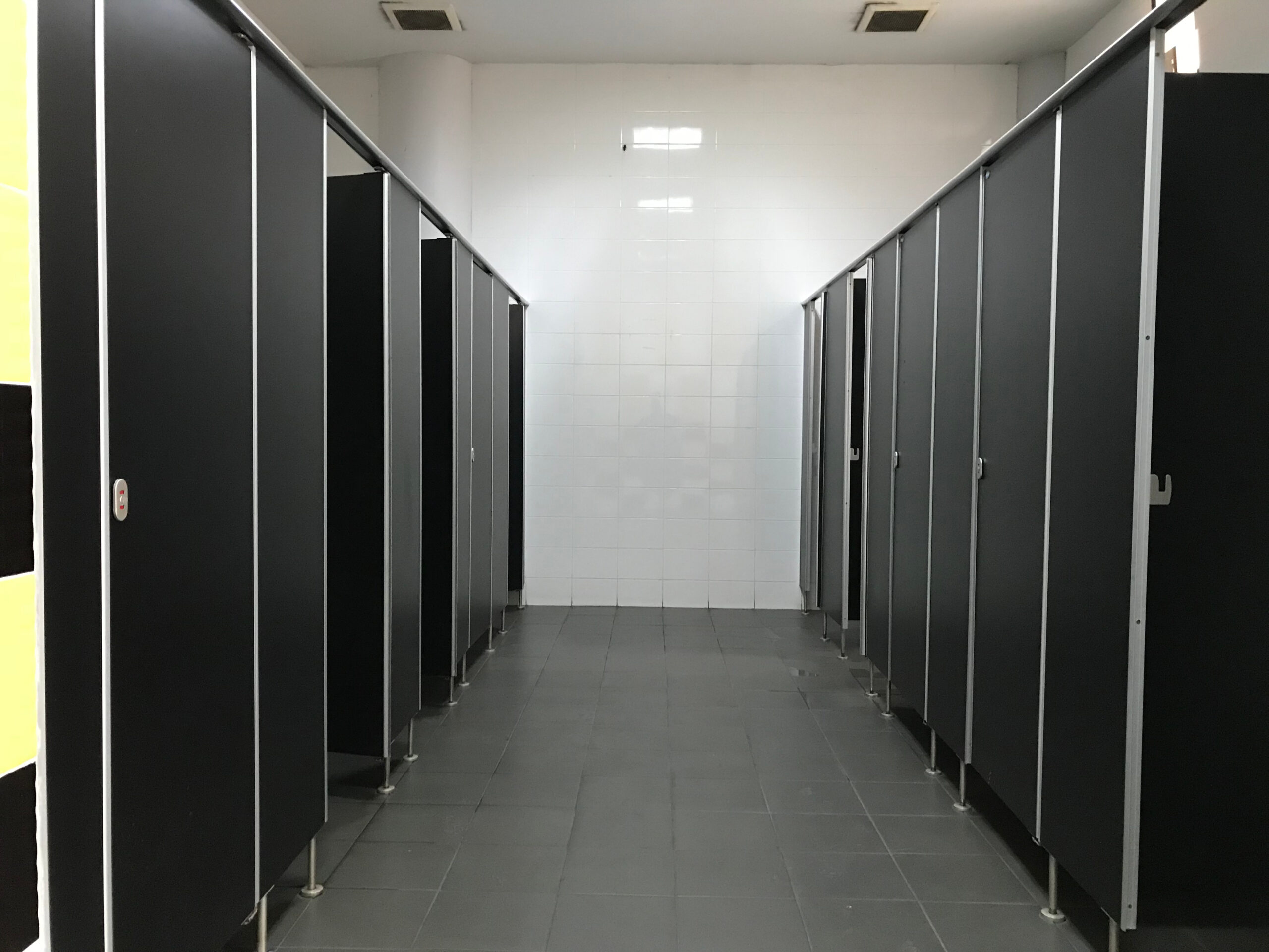 Stainless steel partition hardware parts, as seen in this durable toilet-stall bathroom corridor, last for the long term.